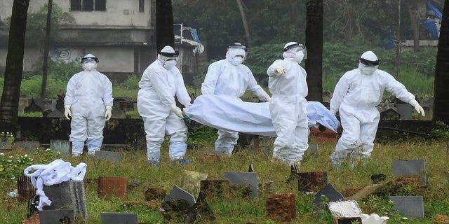 Sept. 5, 2021: People in protective suits prepare to cremate the body of a 12-year-old boy who died of the Nipah virus in Kozhikode, Kerala state, India. 