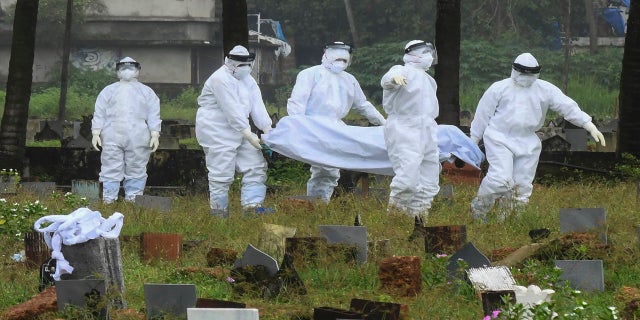 Sept. 5, 2021: People in protective suits prepare to cremate the body of a 12-year-old boy who died of the Nipah virus in Kozhikode, Kerala state, India.