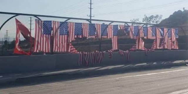The memorial of 13 American flags and one Marine Corps flag was displayed on the fence of the Ivy Street overpass above the 91 Freeway in Riverside