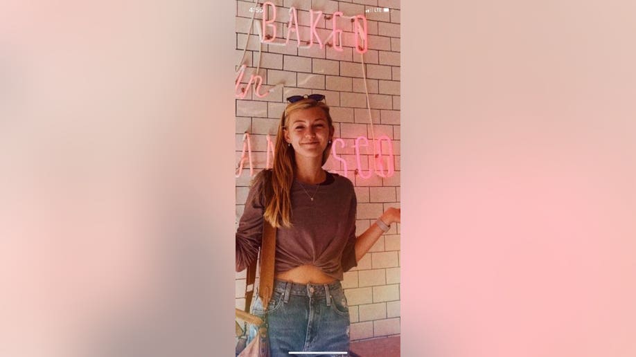 Gabby Petito posing in photo in front of a brick wall