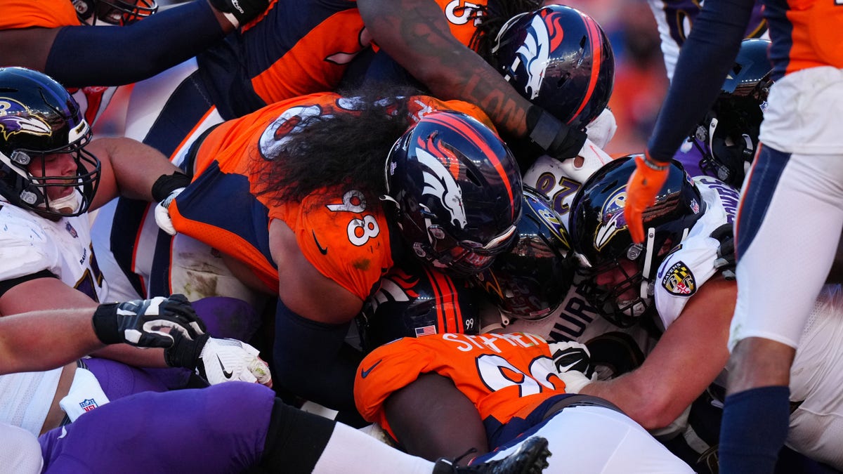 Oct 3, 2021; Denver, Colorado, USA; Baltimore Ravens running back Latavius Murray (28) is tackled by Denver Broncos nose tackle Mike Purcell (98) and linebacker A.J. Johnson (45) and defensive tackle Shamar Stephen (99) in the second half at Empower Field at Mile High.