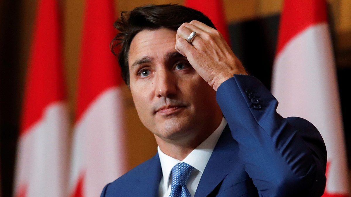 Canada's Prime Minister Justin Trudeau scratches his hair in a blue suit