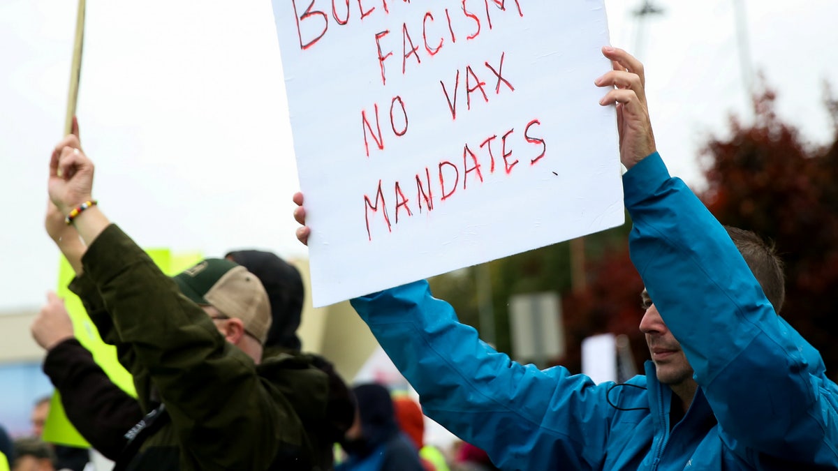 A protester holds a sign claiming Boeing supports fascism as Boeing employees and others protest the company's coronavirus disease (COVID-19) vaccine mandate, outside the Boeing facility in Everett, Washington, October 15, 2021.  REUTERS/Lindsey Wasson