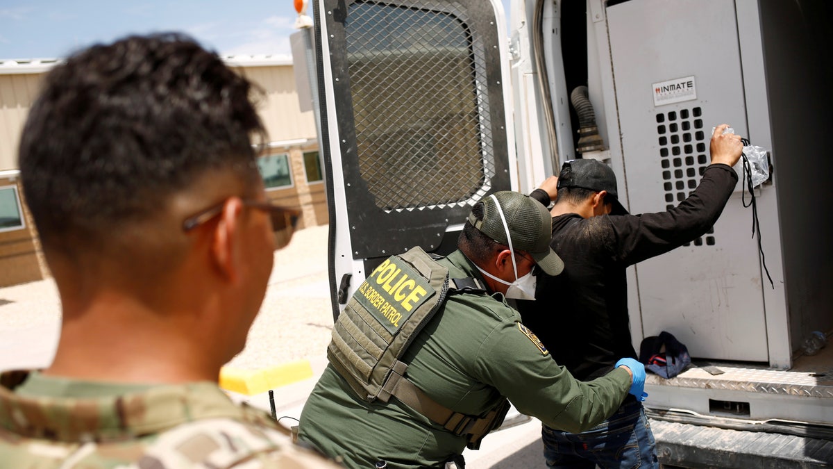 A member of the Border Patrol's Search, Trauma, and Rescue Unit (BORSTAR) pats down a migrant