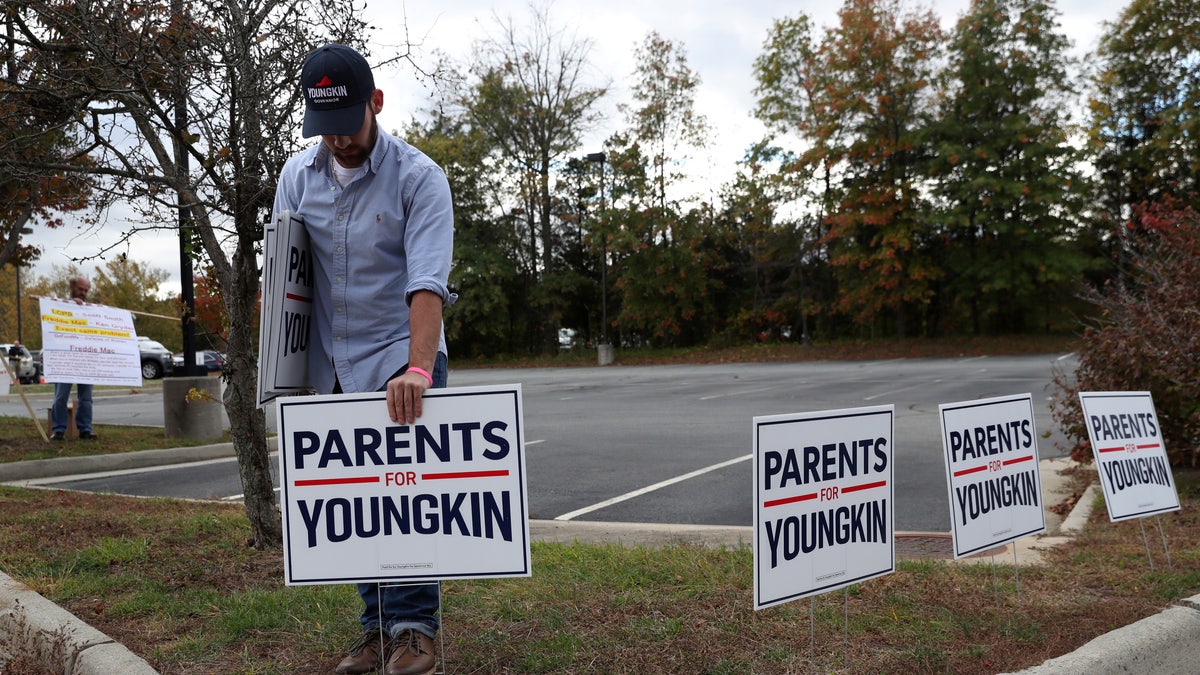 Tristan Thorgersen puts pro-Youngkin signs up as people gather to protest different issues, including the school board’s handling of a sexual assault that happened in a school bathroom in May, vaccine mandates and critical race theory during a Loudoun County School Board meeting