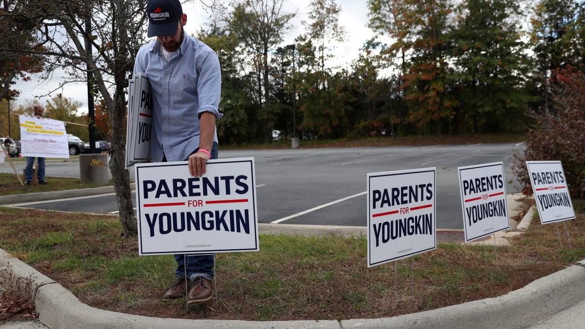 Tristan Thorgersen puts pro-Youngkin signs up as people gather to protest different issues, including the school board’s handling of a sexual assault that happened in a school bathroom in May, vaccine mandates and critical race theory during a Loudoun County School Board meeting