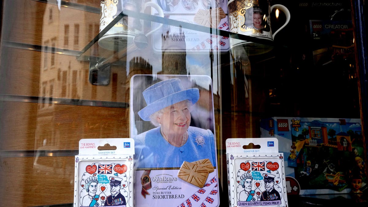 Windsor Castle is reflected in the window of a shop selling royal souvenirs outside the castle in Windsor, England, Friday, Oct. 22, 2021. (AP Photo/Kirsty Wigglesworth)