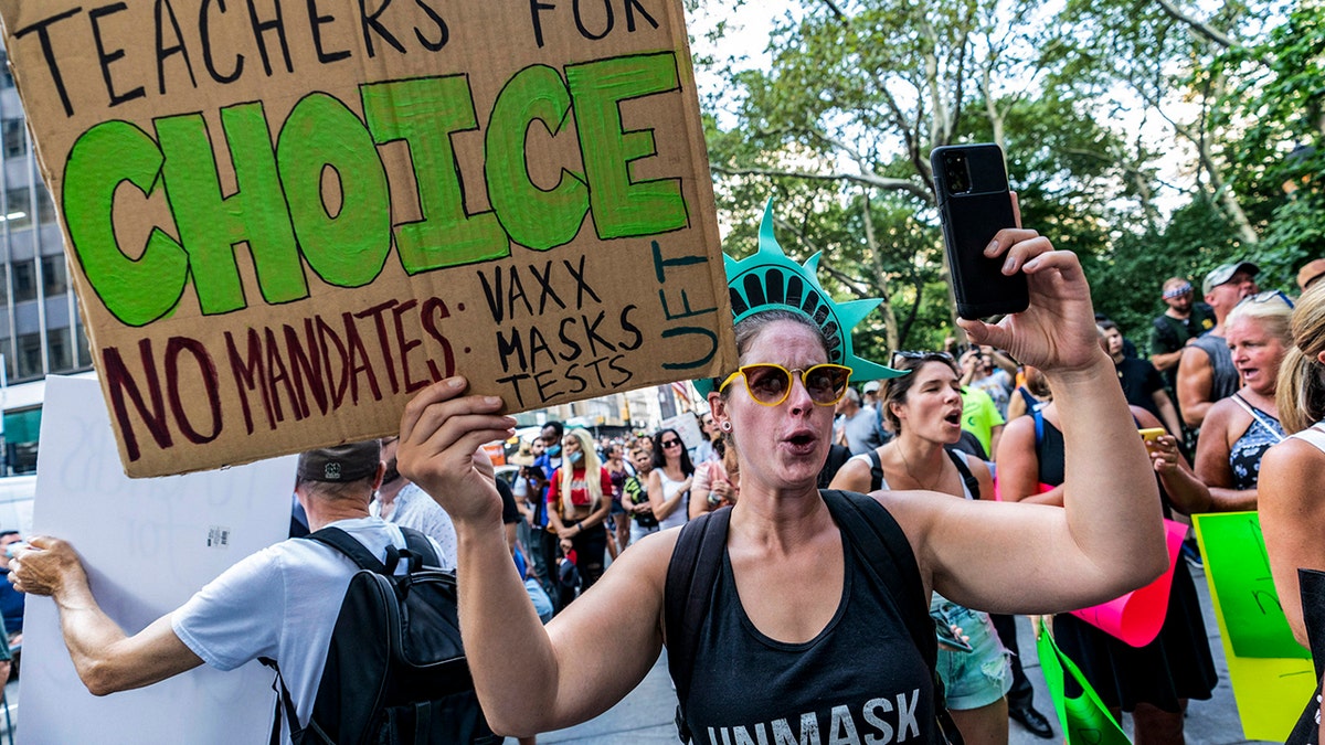 Teachers holding up signs in protest of vaccine mandates