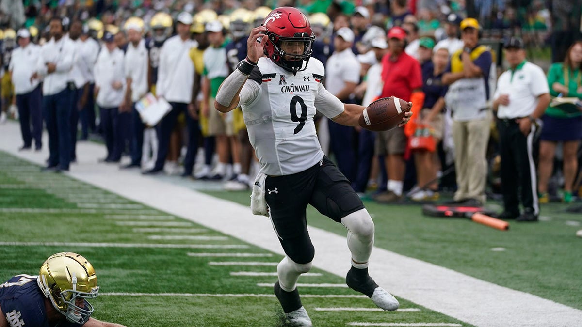 Cincinnati quarterback Desmond Ridder (9) runs in for a touchdown against Notre Dame's JD Bertrand (27) during the second half of an NCAA college football game, Saturday, Oct. 2, 2021, in South Bend, Ind. Cincinnati won 24-13. (AP Photo/Darron Cummings)