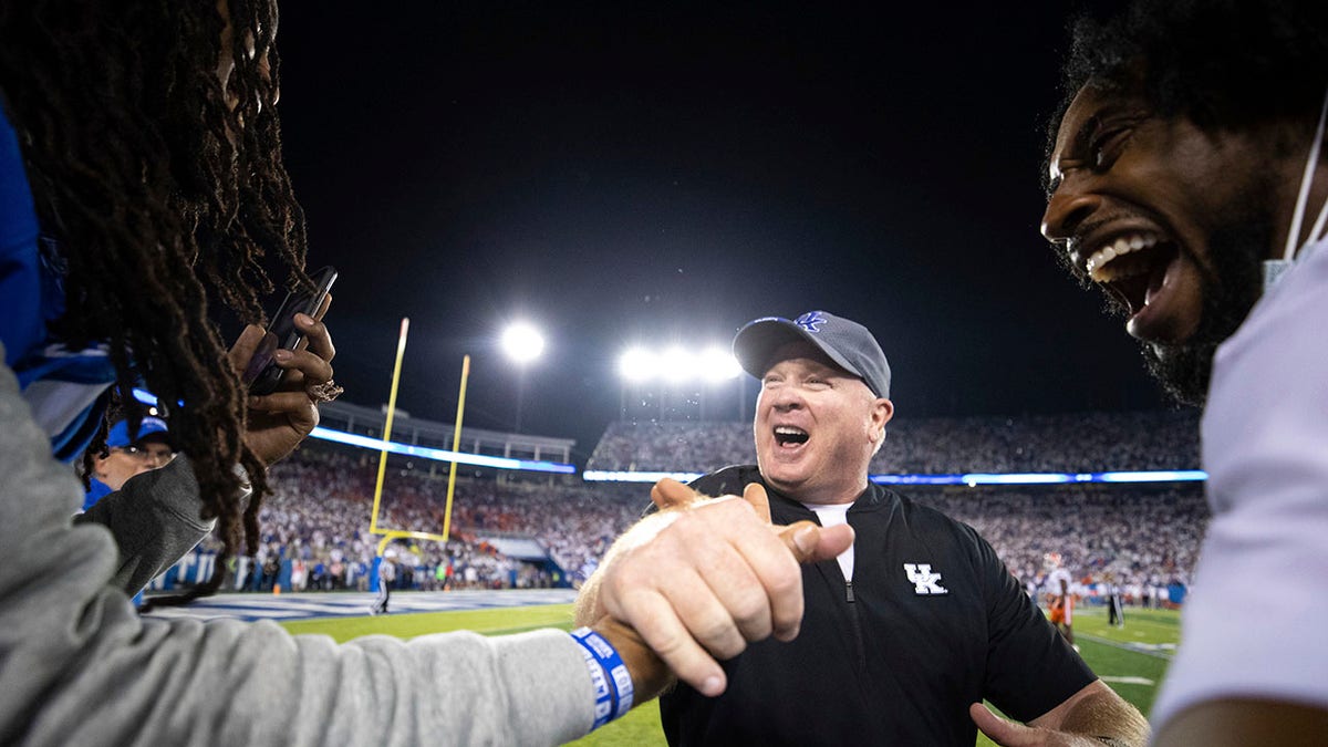 Kentucky head coach Mark Stoops, center, slaps hands with rapper Waka Flocka Flame, left, after winning an NCAA college football game against Florida in Lexington, Ky., Saturday, Oct. 2, 2021. (AP Photo/Michael Clubb)