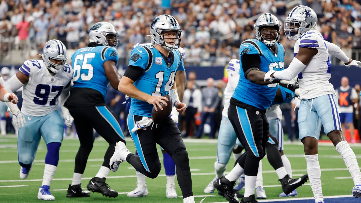 Carolina Panthers quarterback Sam Darnold (14) runs for a touchdown as guard Dennis Daley (65) and guard John Miller (67) block against pressure from Dallas Cowboys defenders Osa Odighizuwa (97) and safety Jayron Kearse, right, in the first half of a NFL football game in Arlington, Texas, Sunday, Oct. 3, 2021.
