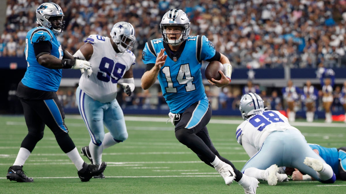 Carolina Panthers quarterback Sam Darnold (14) runs the ball past Dallas Cowboys defensive tackle Justin Hamilton (99) and Quinton Bohanna (98) to the end zone for a touchdown in the first half of an NFL football game in Arlington, Texas, Sunday, Oct. 3, 2021.