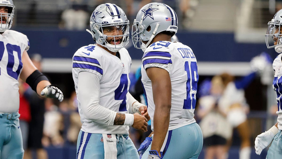 Dallas Cowboys quarterback Dak Prescott (4) and wide receiver Amari Cooper (19) celebrate Cooper's touchdown catch in the second half of an NFL football game against the Carolina Panthers in Arlington, Texas, Sunday, Oct. 3, 2021. (AP Photo/Michael Ainsworth)