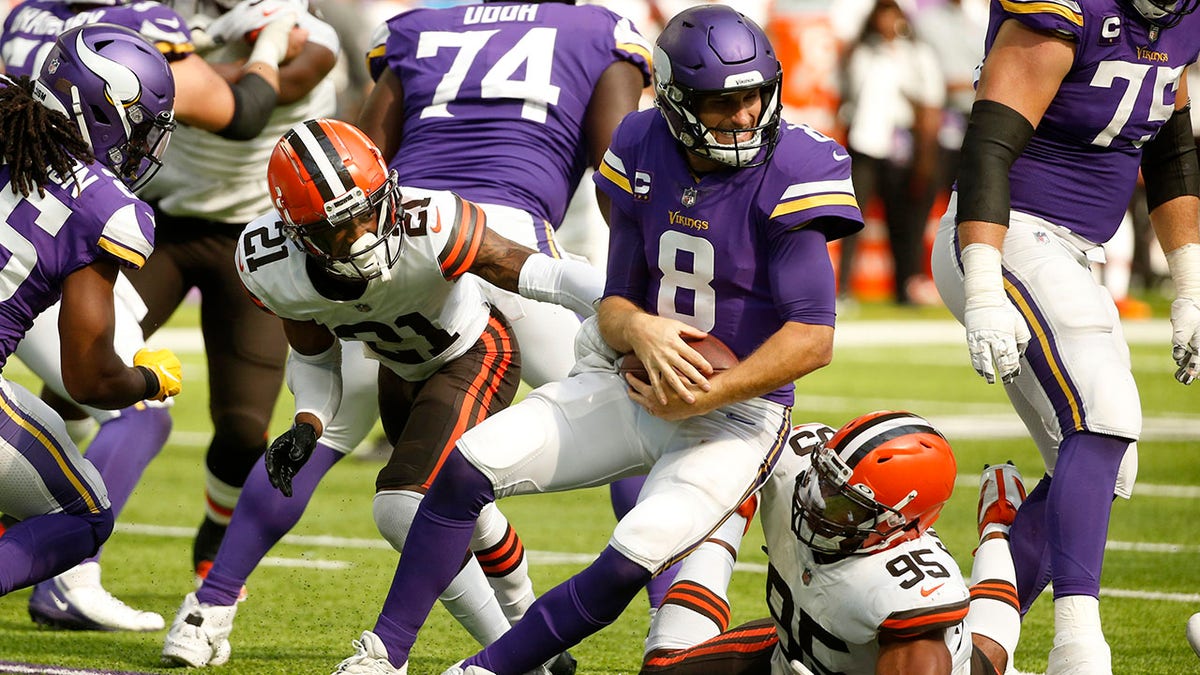 Minnesota Vikings quarterback Kirk Cousins (8) is sacked by Cleveland Browns cornerback Denzel Ward (21) and defensive end Myles Garrett (95) during the second half of an NFL football game, Sunday, Oct. 3, 2021, in Minneapolis.
