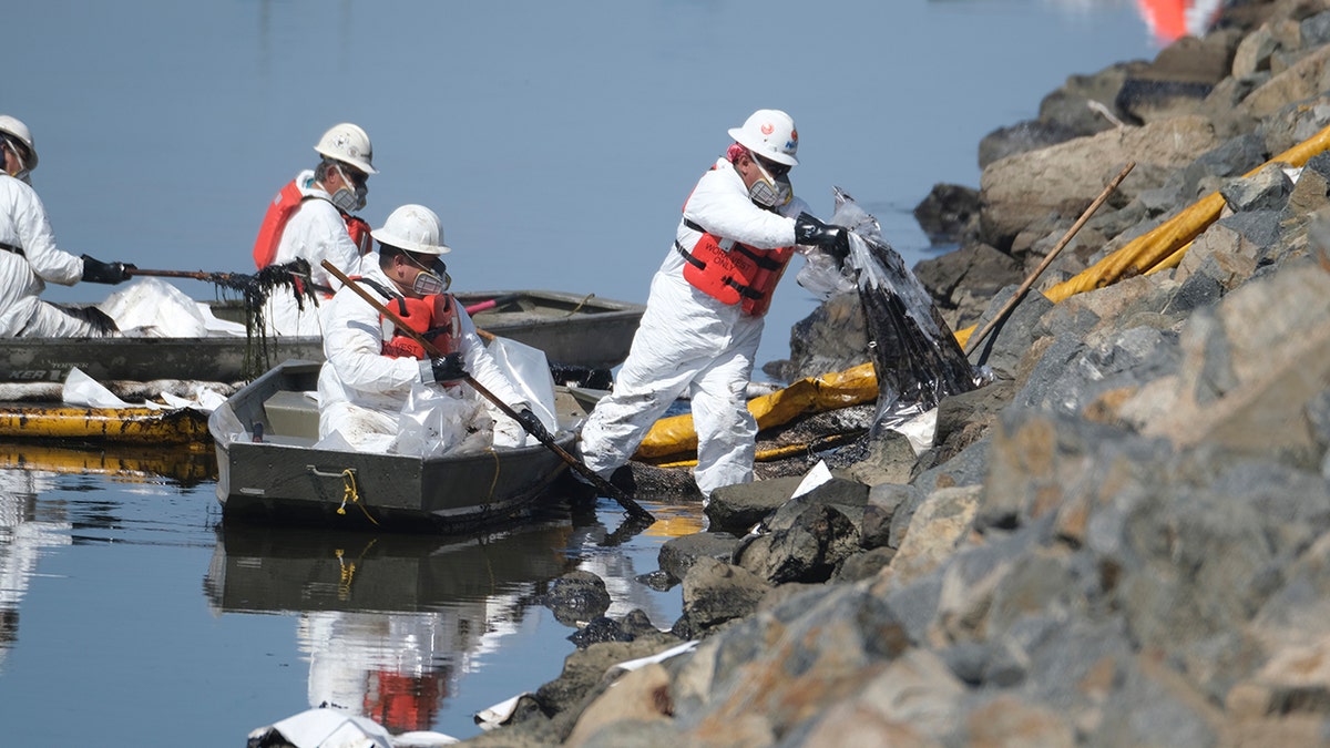 Cleanup contractors unload collected oil in plastic bags trying to stop further oil crude incursion into the Wetlands Talbert Marsh in Huntington Beach, Calif., on Sunday. (AP)
