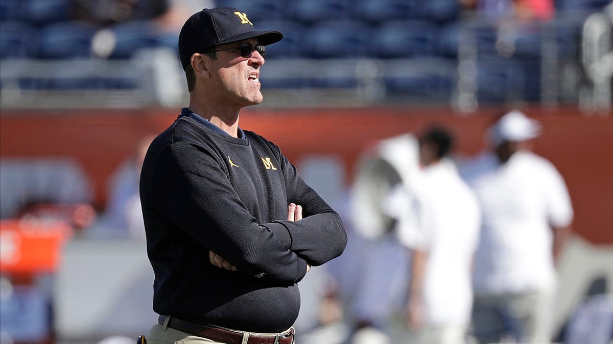 FILE - Michigan head coach Jim Harbaugh watches players warm up before the Citrus Bowl NCAA college football game against Alabama in Orlando, Fla., in this Wednesday, Jan. 1, 2020, file photo. Michigan's Jim Harbaugh and Nebraska's Scott Frost have fallen short of expectations coaching their alma maters. The ninth-ranked Wolverines head to Nebraska this week, and the timing is perfect because both teams are coming off big wins. The vibes are positive around both teams now. They won't be next week for the one that loses. (AP Photo/John Raoux, File)