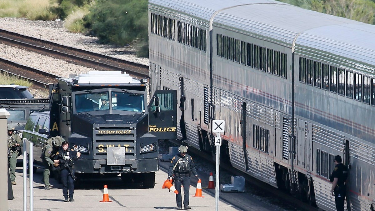 A Tucson Police Department SWAT truck is parked near the last two cars of an Amtrak train in downtown Tucson, Ariz., on Monday. One person is in custody after someone opened fire Monday aboard an Amtrak train parked at the station in the city's downtown. (Mamta Popat/Arizona Daily Star via AP)