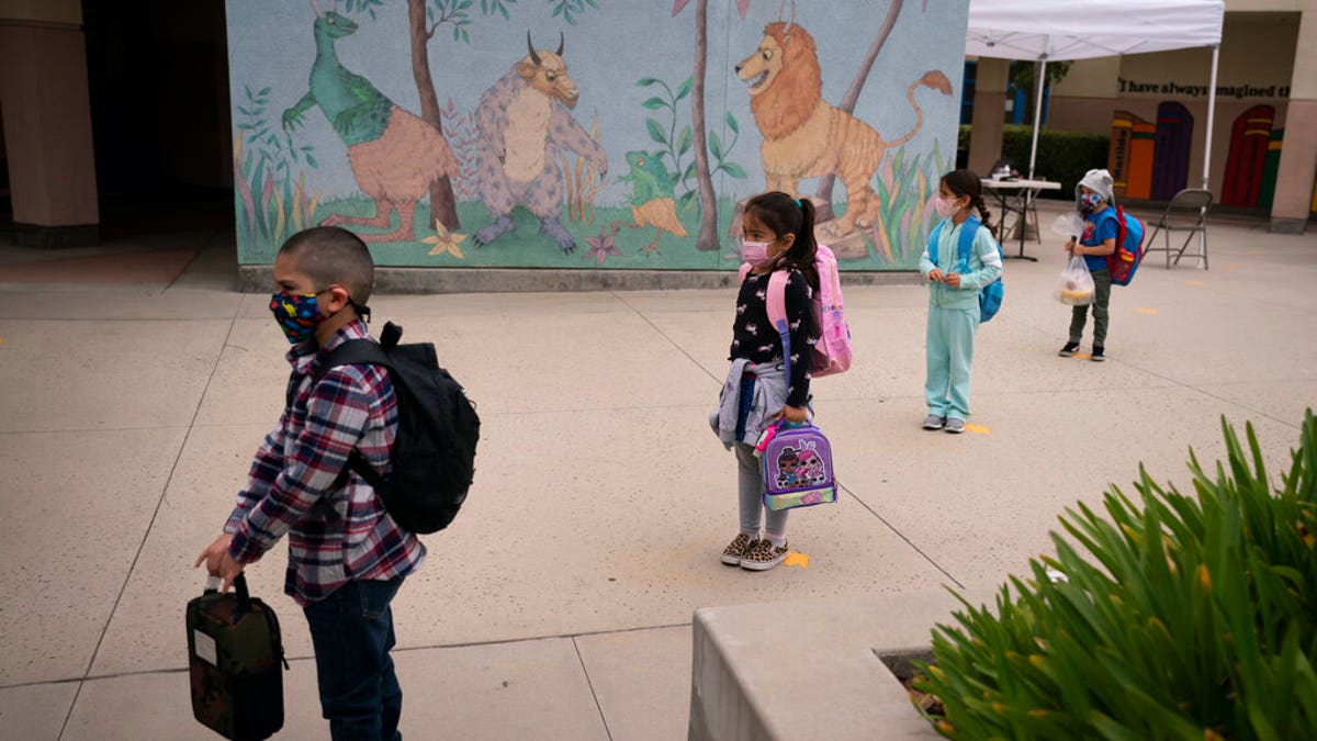 Socially distanced kindergarten students wait for their parents to pick them up on the first day of in-person learning at Maurice Sendak Elementary School in Los Angeles