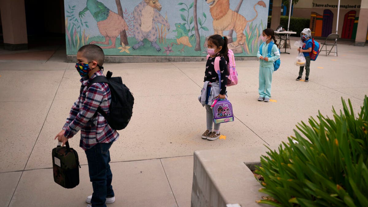 Socially distanced kindergarten students wait for their parents to pick them up on the first day of in-person learning at Maurice Sendak Elementary School in Los Angeles