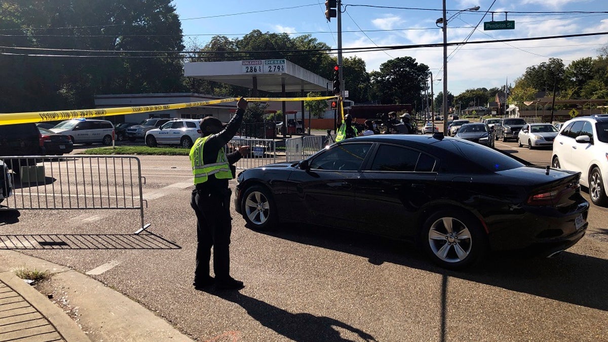 Officers allow a police vehicle to pass under yellow crime scene tape on a street in front of the post office in Memphis. Police said they are investigating a shooting at the post office in Tennessee in which three Postal Service employees were died. (AP Photo/Adrian Sainz)