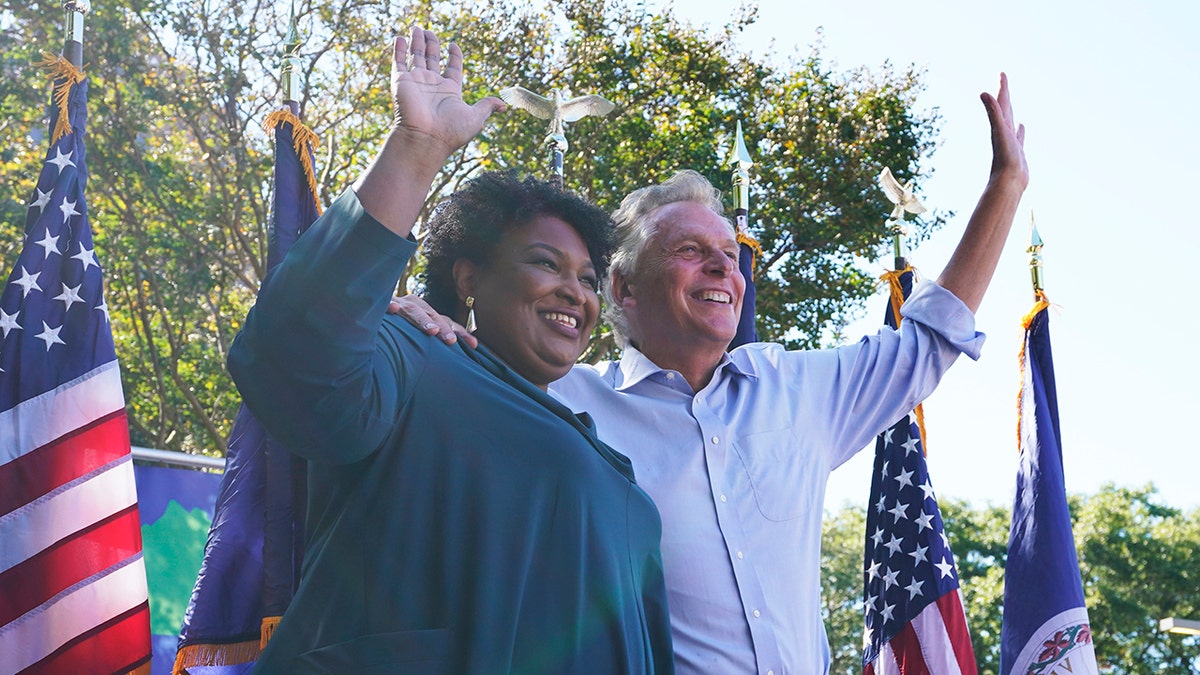 Voting rights activist Stacey Abrams, left, waves to the crowd with Democratic gubernatorial candidate, former Virginia Gov. Terry McAuliffe, right, during a rally in Norfolk, Va., Sunday, Oct. 17, 2021. Abrams was in town to encourage voters to vote for the Democratic gubernatorial candidate in the November election. (AP Photo/Steve Helber)