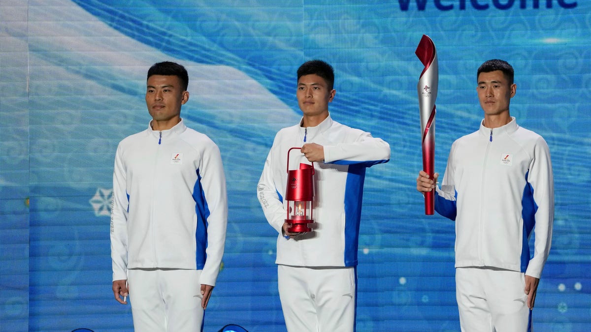 Volunteers hold the Olympic torch and the frame on stage during a welcome ceremony for the Frame of Olympic Winter Games Beijing 2022, held at the Olympic Tower in Beijing, Wednesday, Oct. 20, 2021. A welcome ceremony for the Olympic flame was held in Beijing on Wednesday morning after it arrived at the Chinese capital from Greece.  (AP Photo/Andy Wong)