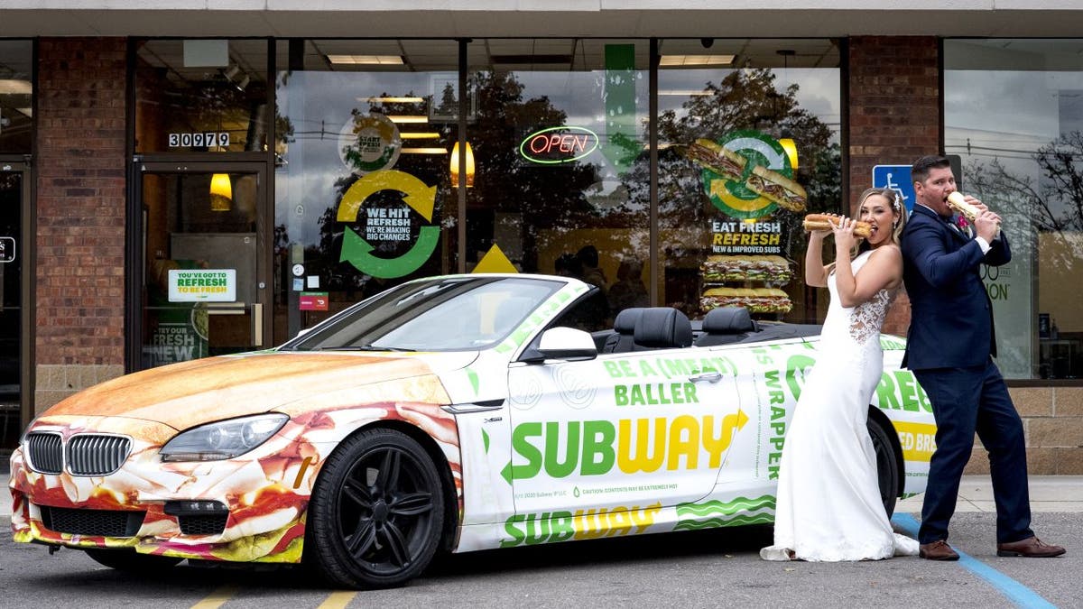 Julie Bushart and Zack Williams posed outside the Subway where they first met each other in 2017 with a Subway-themed convertible sports car and foot-long sandwiches.