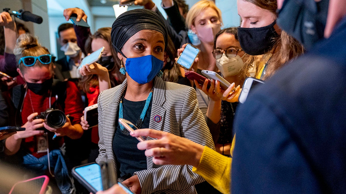 Ilhan Omar speaks to reporters while wearing a mask