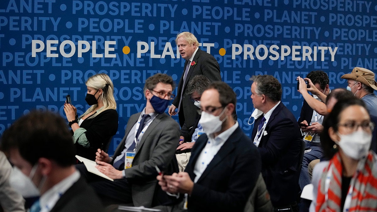 British Prime Minister Boris Johnson walks past a sign reading "People, Planet, Prosperity" as he arrives for a press conference at the La Nuvola conference center for the G20 summit in Rome, Sunday, Oct. 31, 2021. Leaders of the world's biggest economies made a compromise commitment Sunday to reach carbon neutrality "by or around mid-century" as they wrapped up a two-day summit that was laying the groundwork for the U.N. climate conference in Glasgow, Scotland. (AP Photo/Kirsty Wigglesworth)