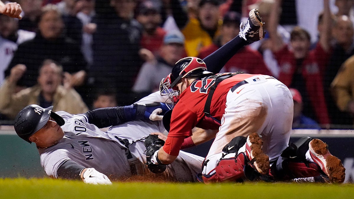 New York Yankees' Aaron Judge is tagged out at the plate by Boston Red Sox catcher Kevin Plawecki as he tries to score on a single by Giancarlo Stanton in the sixth inning of an American League Wild Card playoff baseball game at Fenway Park, Tuesday, Oct. 5, 2021, in Boston.