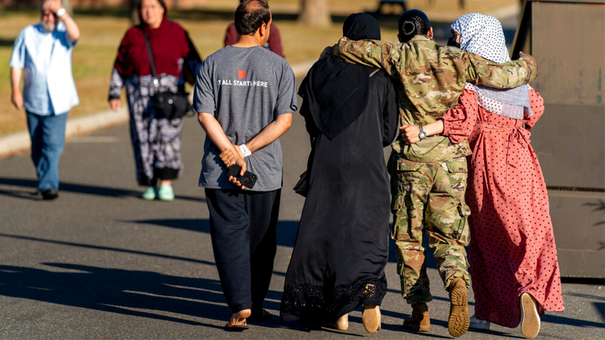 FILE: A female member of the military puts her arms around two female Afghan refugees after they spoke with Secretary of Defense Lloyd Austin as he visits an Afghan refugee camp on Joint Base McGuire Dix Lakehurst, N.J.