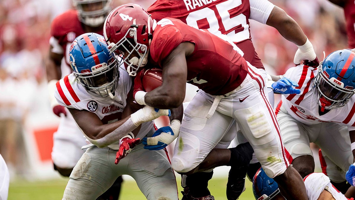 Alabama running back Brian Robinson Jr. (4) runs by Mississippi linebacker Lakia Henry (0) during the first half of an NCAA college football game, Saturday, Oct. 2, 2021, in Tuscaloosa, Ala.