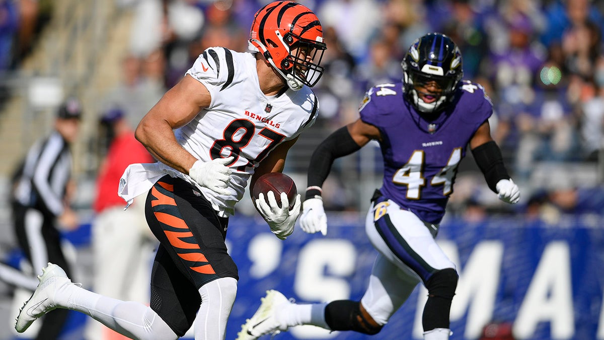 Cincinnati Bengals tight end C.J. Uzomah, left, runs with the ball next to Baltimore Ravens cornerback Marlon Humphrey after making a catch before scoring a touchdown against the Baltimore Ravens during the first half of an NFL football game, Sunday, Oct. 24, 2021, in Baltimore.