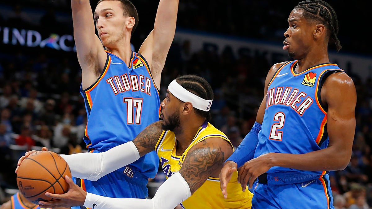 Los Angeles Lakers forward Carmelo Anthony (7) goes against Oklahoma City Thunder forward Aleksej Pokusevski (17) and guard Shai Gilgeous-Alexander (2) during the first half of an NBA basketball game, Wednesday, Oct. 27, 2021, in Oklahoma City.