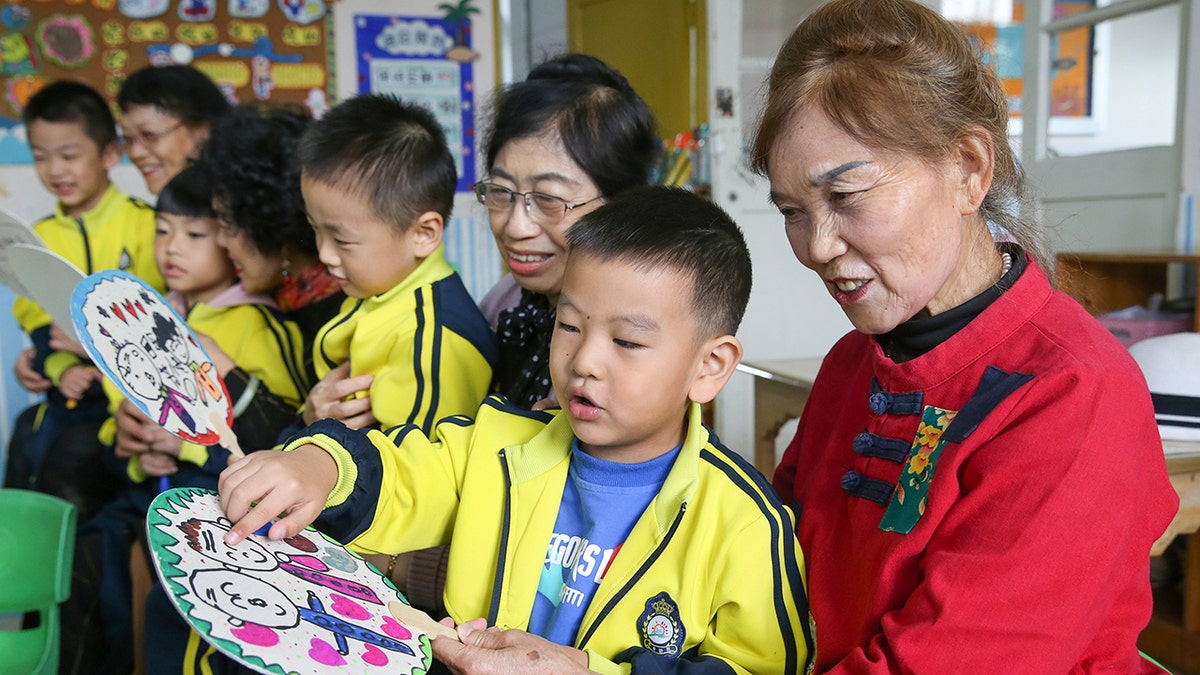 Children give handmade fans to their grandparents in a kindergarten of Lianyungang City, east China's Jiangsu Province in October. A proposed law in China would punish parents or guardians if their children misbehaved.