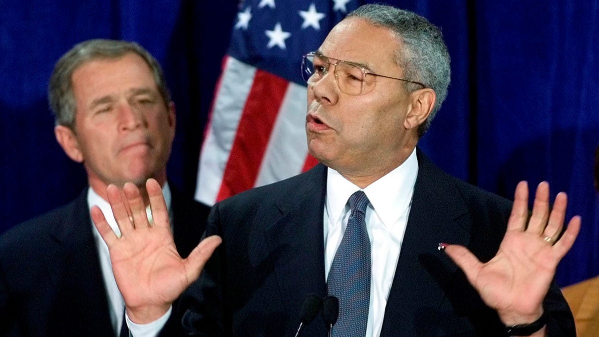 U.S. President-elect Bush (L) listens as retired General Colin Powell speaks to supporters and the press after Bush annouced Powell would serve as his Secretary of State in the his administration during a ceremony in Crawford, Texas