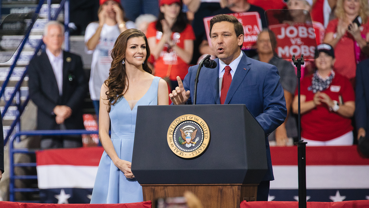 Rep. Ron DeSantis, then a Republican candidate for governor of Florida, right, speaks as his wife, Casey DeSantis, center, and President Trump (not pictured) look on during a campaign rally in Estero, Florida, on Wednesday, Oct. 31, 2018.