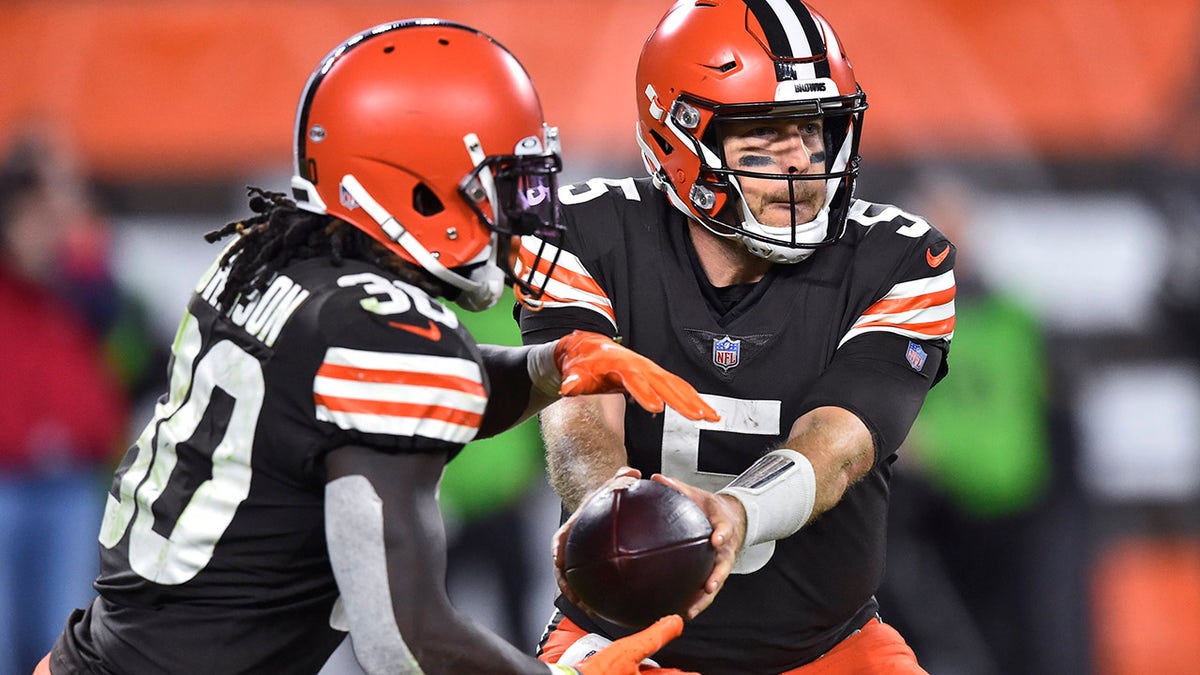 Cleveland Browns quarterback Case Keenum (5) hands the ball off to running back D'Ernest Johnson (30) during the second half of the team's NFL football game against the Denver Broncos, Thursday, Oct. 21, 2021, in Cleveland. 
