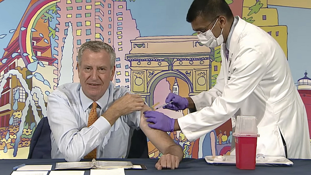 New York Mayor Bill de Blasio, left, receives a COVID-19 Moderna vaccine booster from New York City Health Commissioner Dr. Dave Chokshi during the mayor's daily news briefing on Monday.
