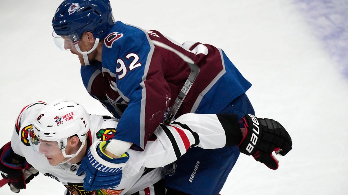 Colorado Avalanche left wing Gabriel Landeskog, top, holds Chicago Blackhawks left wing Dominik Kubalik and is called for a penalty during the second period of an NHL hockey game Wednesday, Oct. 13, 2021, in Denver.