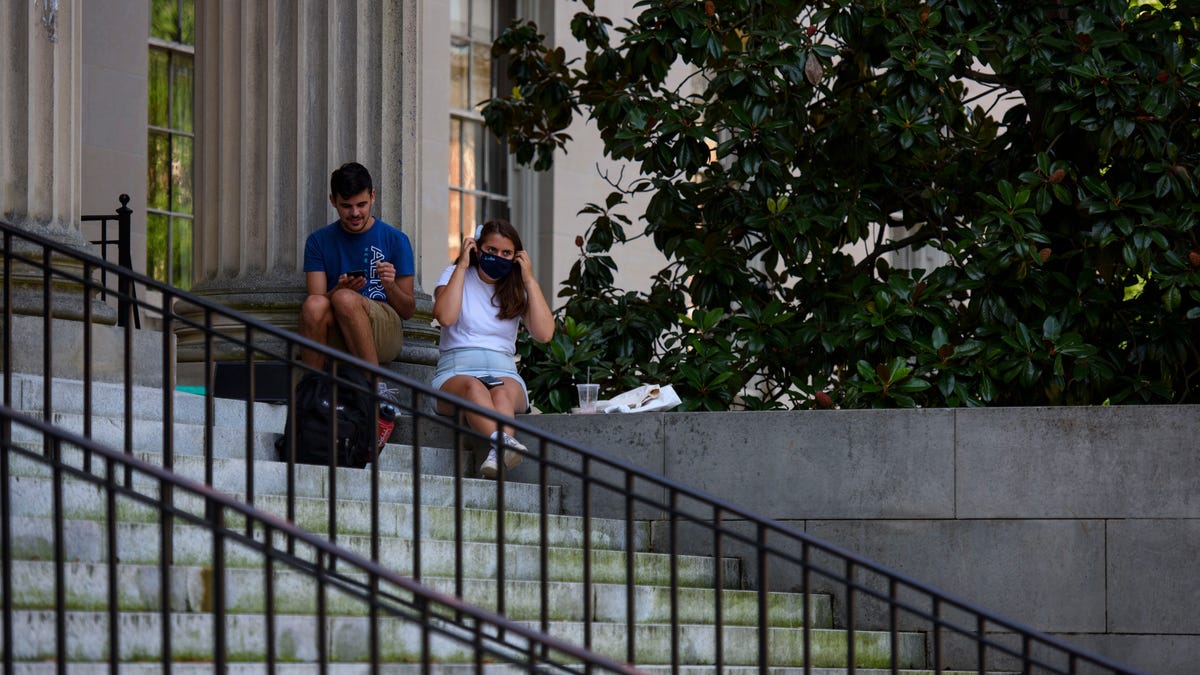 CHAPEL HILL, NC - AUGUST 18: A person puts on a mask outside the closed Wilson Library at the campus of the University of North Carolina at Chapel Hill on August 18, 2020 in Chapel Hill, North Carolina. The school halted in-person classes and reverted back to online courses after a rise in the number of COVID-19 cases over the past week. (Photo by Melissa Sue Gerrits/Getty Images)