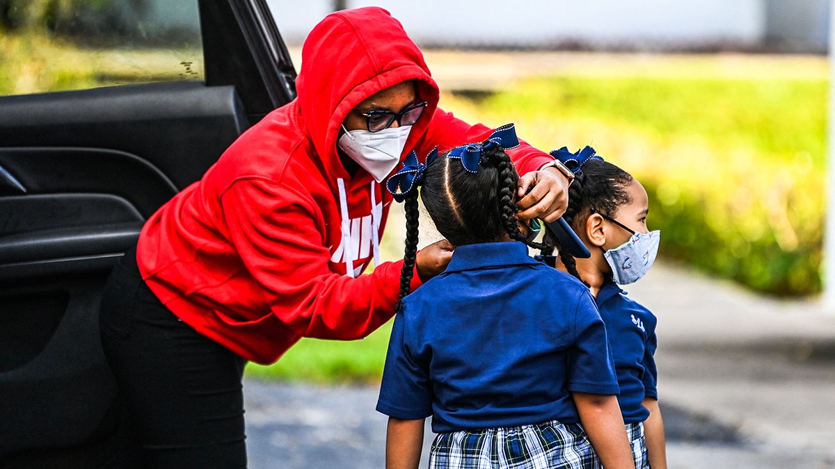 A mother adjusts the face mask of her child as she enters the St. Lawrence Catholic School on the first day of school after summer vacation in north of Miami, on Aug. 18, 2021. (Photo by CHANDAN KHANNA/AFP via Getty Images)