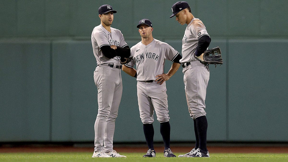 Joey Gallo #13, Brett Gardner #11 and Aaron Judge #99 of the New York Yankees stand in the outfield during a pitching change against the Boston Red Sox during the seventh inning of the American League Wild Card game at Fenway Park on October 05, 2021 in Boston, Massachusetts.