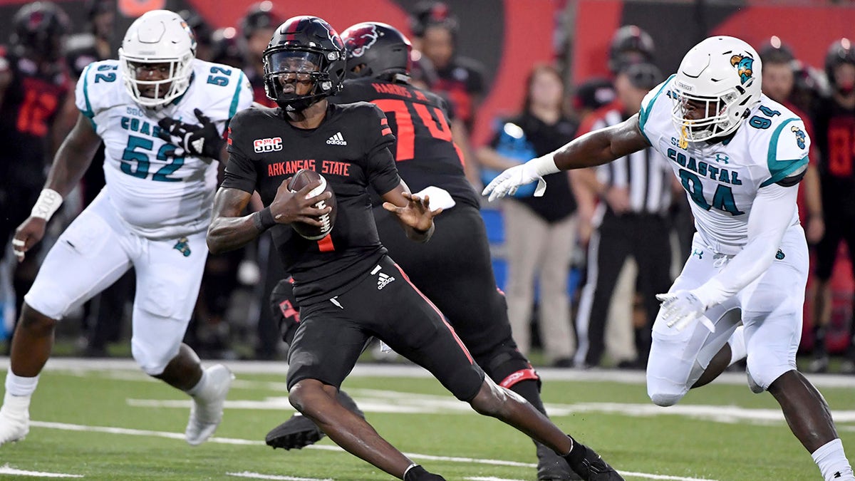 Arkansas State quarterback James Blackman (1) tries to get away from Coastal Carolina defenders C.J. Brewer (52) and Jeffrey Gunter (94) during the first half of an NCAA college football game Thursday, Oct. 7, 2021, in Jonesboro, Ark.