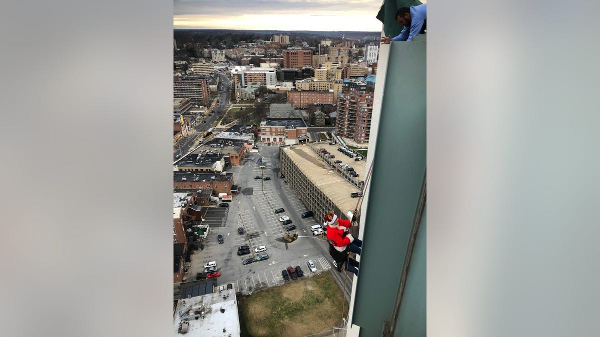 Janice Dean rappelling down the side of a building in a Santa suit.