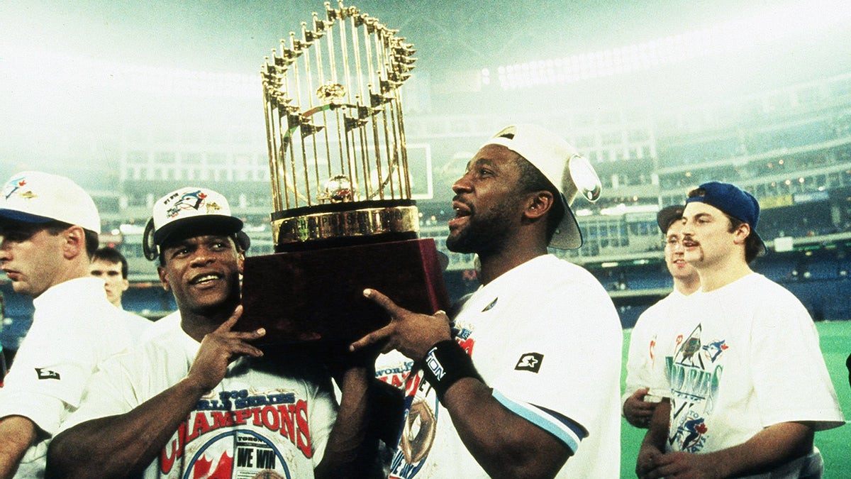 TORONTO, ON - OCTOBER 23: Rickey Henderson (L) and Joe Carter of the Toronto Blue Jays carry the World Series trophy after the Blue Jays victory during World Series game six between the Philadelphia Phillies and Toronto Blue Jays on October 23, 1993 at the Skydome in Toronto, Ontario, Canada. The Blue Jays defeated the Phillies 8-6.