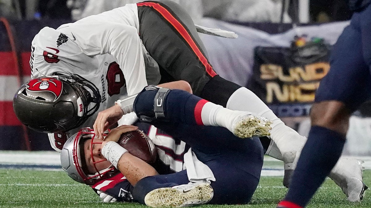 New England Patriots quarterback Mac Jones, bottom, is sacked by Tampa Bay Buccaneers linebacker Joe Tryon-Shoyinka (9) during the second half of an NFL football game, Sunday, Oct. 3, 2021, in Foxborough, Mass.