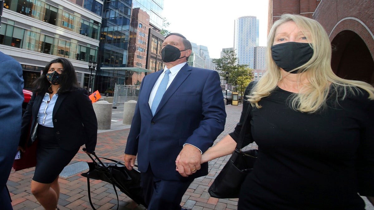 John Wilson, center, holds his wife's hand, right, as he departs federal court, in Boston, on Sept. 13. Wilson and another parent, Gamal Abdelaziz, who are the first to stand trial in the college admissions bribery scandal, used lies and money to steal coveted spots at prestigious schools their kids couldn't secure on their own, a prosecutor said Wednesday before jurors decide if the men are guilty. ?