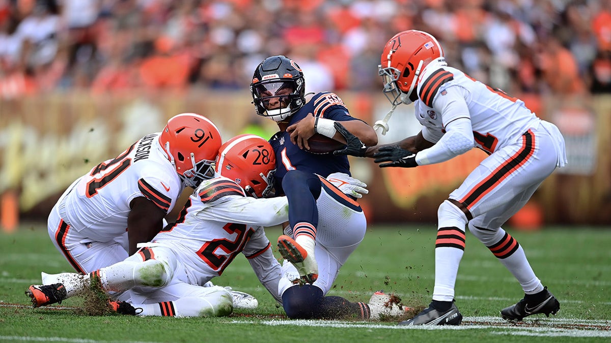 Chicago Bears quarterback Justin Fields slides for a short gain against Cleveland Browns defensive end Joe Jackson (91), linebacker Jeremiah Owusu-Koramoah (28) and cornerback Denzel Ward (21) during the second half of a game against the Cleveland Browns, Sunday, Sept. 26, 2021, in Cleveland.