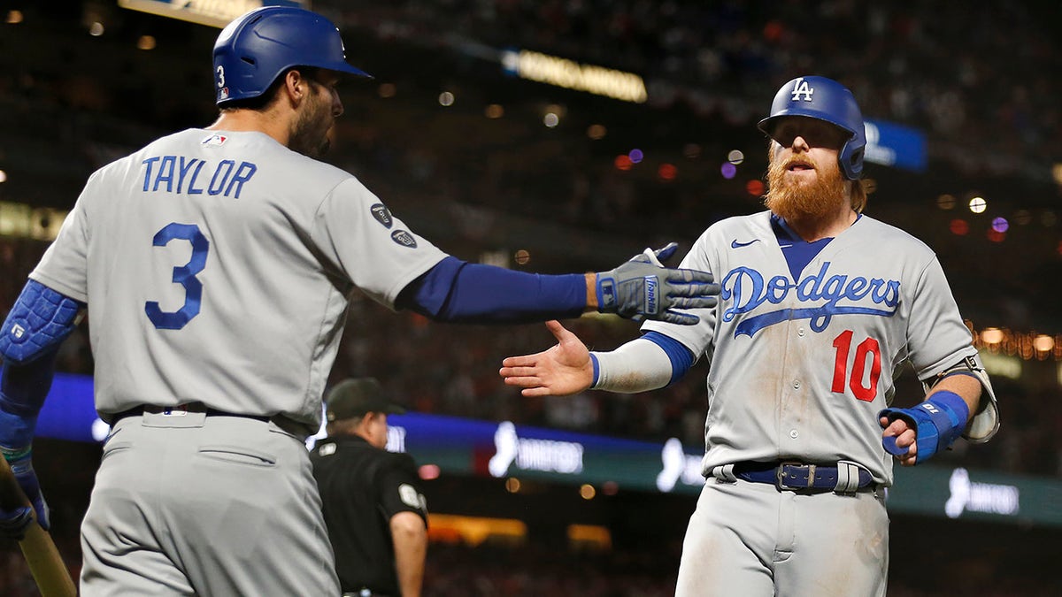 Los Angeles Dodgers' Justin Turner, right, is congratulated by Chris Taylor after scoring against the San Francisco Giants during the ninth inning of Game 5 of a baseball National League Division Series Thursday, Oct. 14, 2021, in San Francisco.